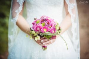 Braut mit Brautstrauß in pink und Schleier mit Spitze