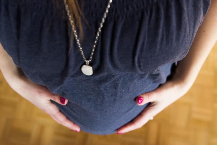 Nahaufnahme vom Babybauch einer Frau mit dunkelblauem Shirt