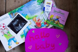 Bild mit Ultraschallfoto eines Babys, Schild "hallo baby", Buch für Kinder "Wir sind jetzt vier" und Folio Tabletten