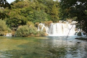 Wasserfälle und see mit grünen Büschen und Bäumen drum herum - Nationalpark Krka in Kroatien - unser Familienurlaub