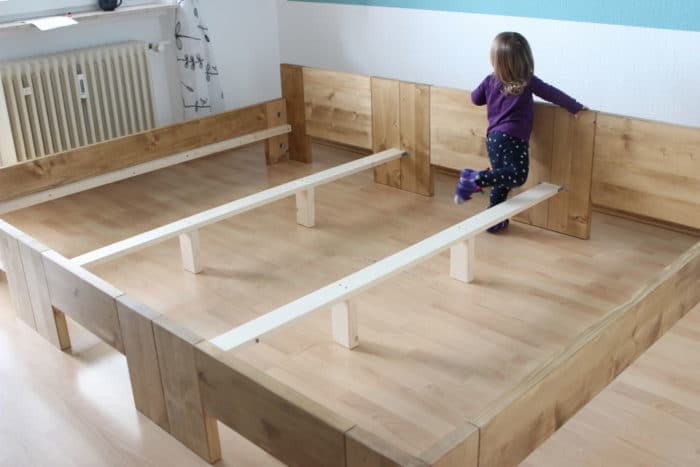 Mädchen steht beim Aufbau des Familienbettes beim aufgebauten Bettgestellt - unser neues großes Familienbett - kein DIY oder IKEA Hack sondern ein gekauftes Familienbett von RIMA