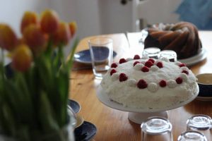 einfache Torte mit Kokos, Sahne und Himbeeren - Rezept für Raffaellotorte mit Himbeeren - Kuchen steht auf dem Tisch für den Muttertag