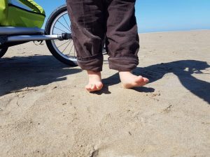 kleine nackige Kinderfüße stehen im Sand am Strand