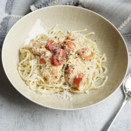 Pasta mit Garnelen und Tomaten in einem tiefen teller mit Käutern und Parmesan garniert