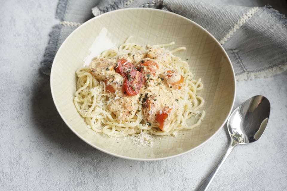 Pasta mit Garnelen und Tomaten in einem tiefen teller mit Käutern und Parmesan garniert