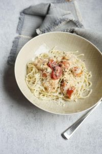 Teller mit Spaghetti, Garnelen und halbierten kleinen Tomaten in Frischkäsesoße - Rezept für Nudeln mit Fisch