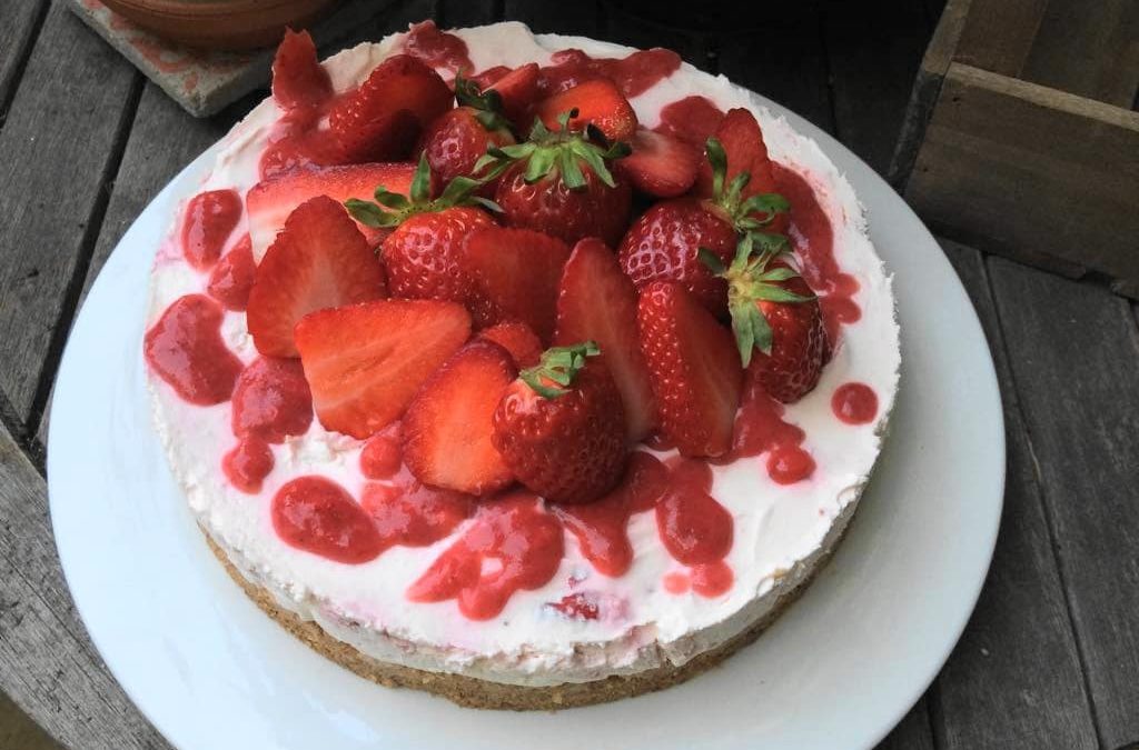 No bake Kuche mit Erdbeeren und Erdbeerpüree auf einem großen weißen Teller