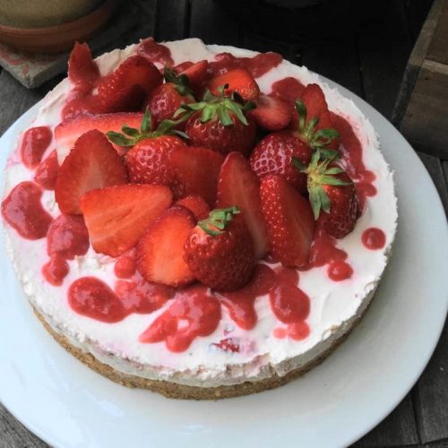 No bake Kuche mit Erdbeeren und Erdbeerpüree auf einem großen weißen Teller