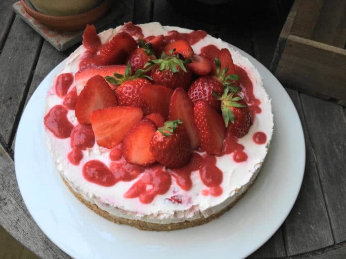 No bake Kuche mit Erdbeeren und Erdbeerpüree auf einem großen weißen Teller