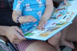 Mädchen liest im Buch Müllabfuhr aus der Kinderbuch Reihe Was ist was Kindergarten für Kinder ab 2 oder 3 Jahren