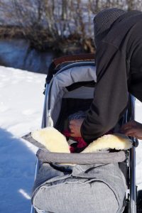 Papa und Baby im Kinderwagen - kuschelig warm hält der Kinderwagenfußsack aus Lammfell vom Fellhof