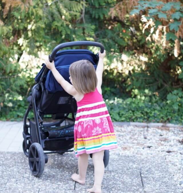 große Schwester schiebt die kleine Schwester im Buggy