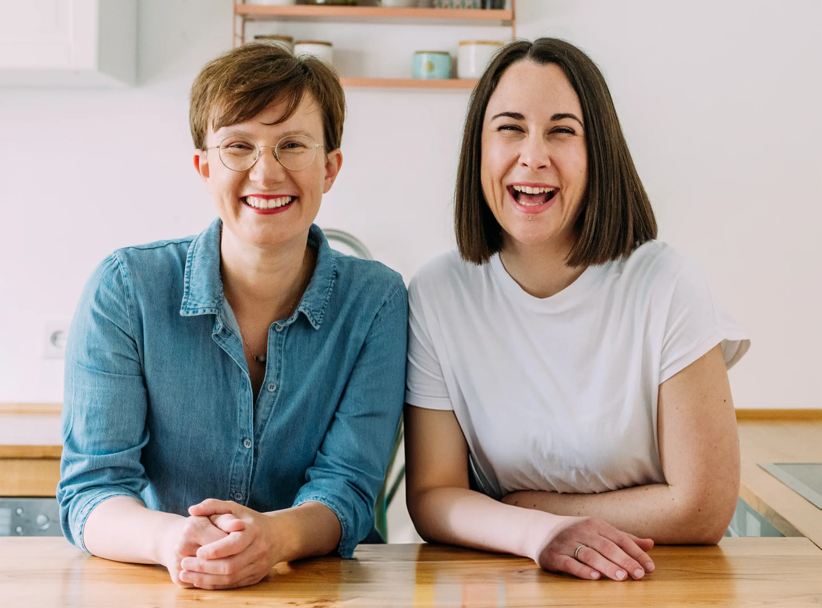 Lena und Annina von breifreibaby lehnen sich nebeneinander auf eine Kücheninsel und lächeln freundlich in die Kamera