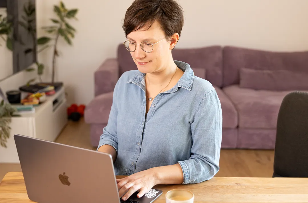 Lena Merz, Gründerin von breifreibaby, sitzt an einem Holztisch und arbeitet am Laptop